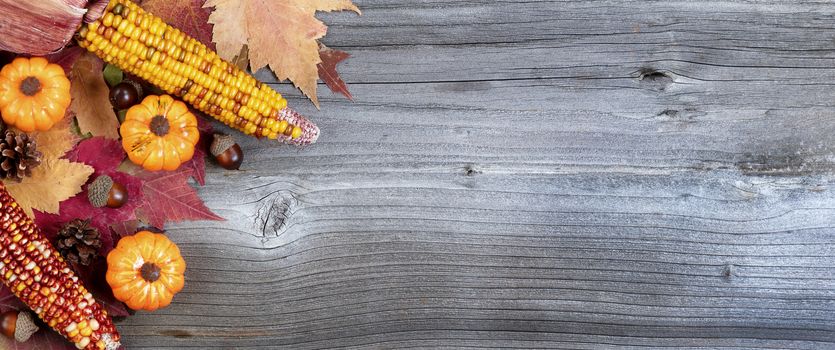 Left corner border of colorful Autumn decorations over a weathered wooden background