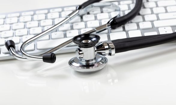 Medical health care concept with traditional stethoscope and computer keyboard in background 