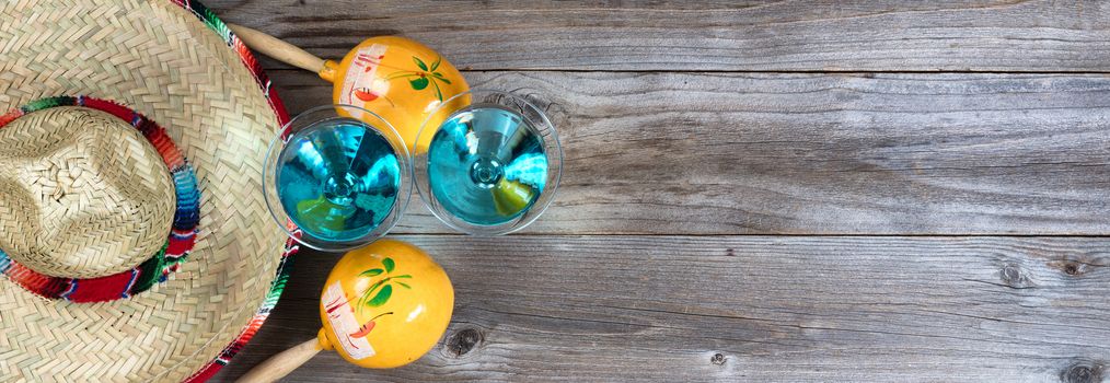 Flat lay view of yellow maracas, sombrero and drinks on rustic red wooden boards for Cinco de Mayo concept. 