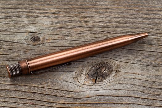 Close up of antique metal pen on weathered wood.