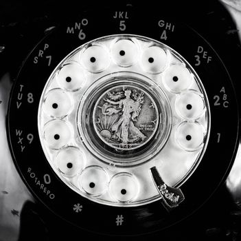 Vintage rotary phone dial with old silver coin 