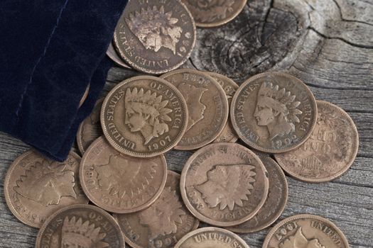 Close up view of United States Vintage pennies spilling out of small bag on rustic wood