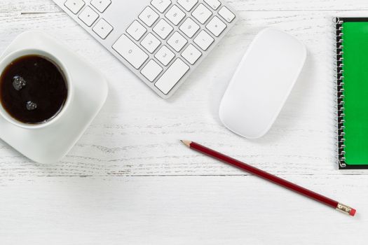 Wooden office table with computer, notepad, mouse, sharpen pencil, and black coffee. Top view angle with copy space. 