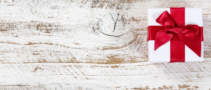 Giftbox with red bow on rustic wood in flat lay view 