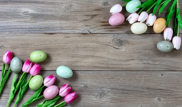 Tulips and colorful eggs on rustic wooden boards for Easter Background 