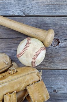 Vertical image of a partial old worn glove, bat and used baseball on rustic wood 