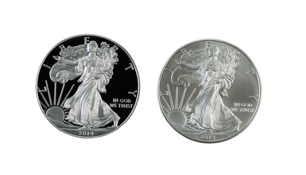 Closeup photo of a proof and uncirculated American Silver Eagle Dollar Coins side by side isolated on white 