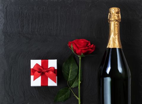 Anniversary background with champagne and gifts on natural black slate stone 