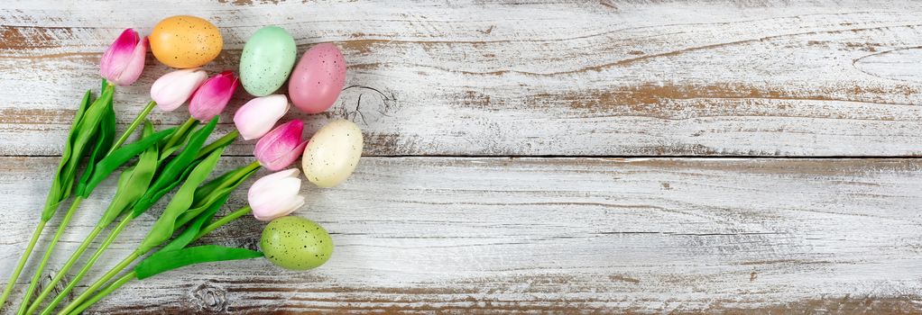 Tulips and colorful eggs on rustic white wooden boards for Easter Background 