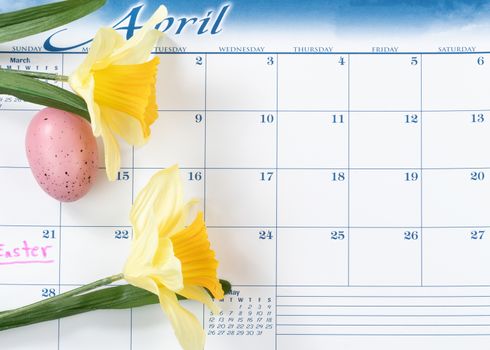Easter holiday marked on calendar with yellow daffodils and colorful egg 