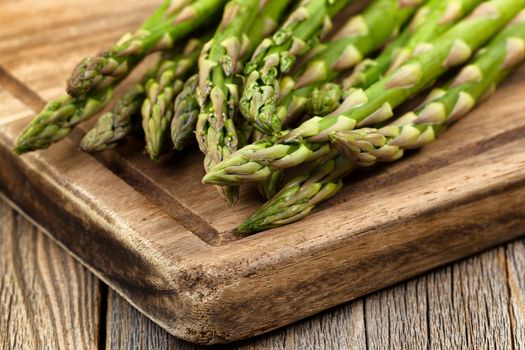 Close up of fresh asparagus on wooden server board. Selective focus on tips of asparagus. 