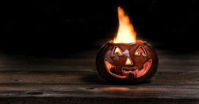 Fiery Halloween pumpkin on wood at night