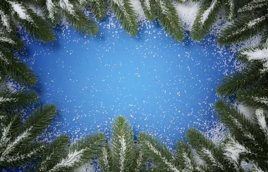 Merry Christmas holiday full circle snowy fir branch border on blue background for the seasonal tradition   