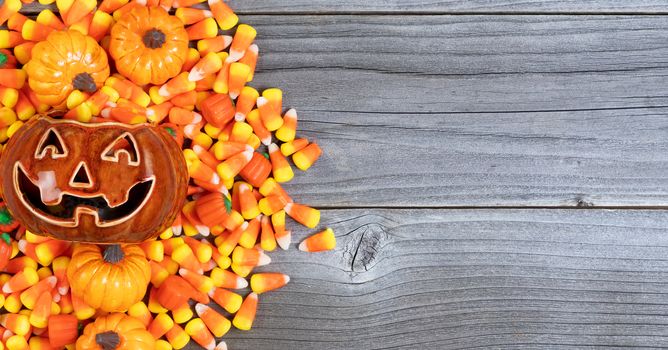 Halloween scary pumpkin with candy treats on weathered wood in flat lay format with copy space