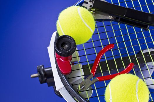 Tennis racket in stringing machine being repaired on blue background