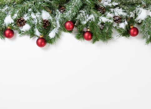 Christmas snowy tree branches and red ornaments on white background