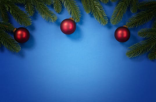 Merry Christmas holiday top circle fir branches and red ball ornaments border on blue background for the seasonal tradition   