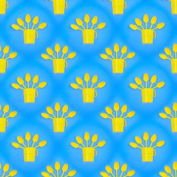 Seamless abstract background with yellow plastic cups and spoons on a blue background.