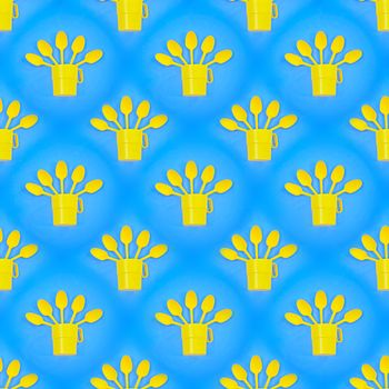 Seamless abstract background with yellow plastic cups and spoons on a blue background.