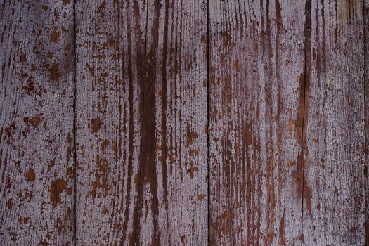 Old red wooden texured door surface closeup. Relief on surface. Stock photo of old wooden door pattern of aged boards with scratches. Red and gray colors on photo.