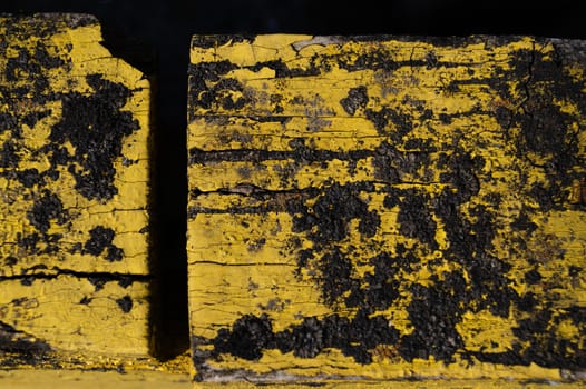 A part of old yellow wooden fence. The yellow paint on wood is old and cracked. Perfect painted wooden texture.