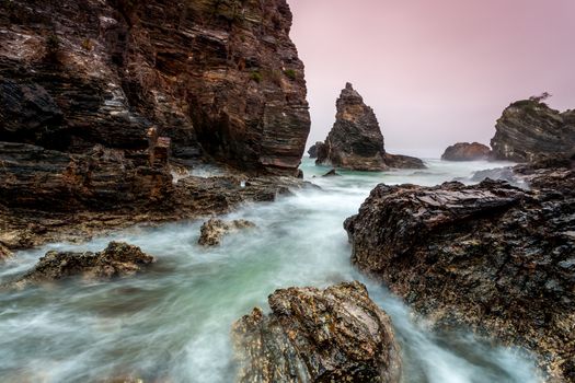 Jagged beach and waves if water rushes in and slowly retreats only to be ushered forth again with a stronger force, the constant ebb and flow of the tide and the creaking and moaning of the rocks