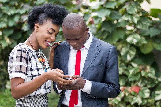 Young people happy to consult together a mobile phone to the outdoors.