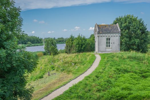 small shed looking like a crypt with path at the lake