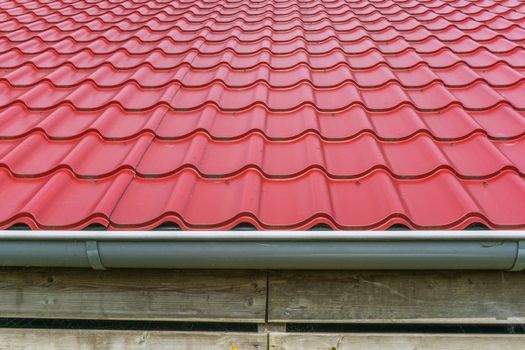 red glossy rooftop tiling with drainpipe