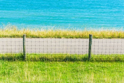 Ocean water landscape with grass fence and road