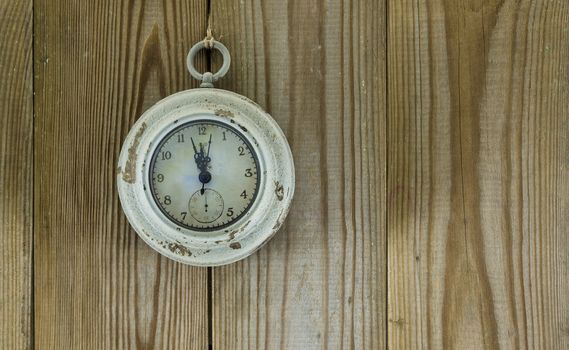 old clock indicates five to twelve on wooden background
