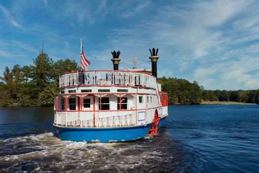 A traditional river boat pulling away from the dock in a lake