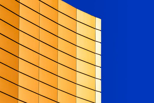 architectural abstract pattern fragment of a wall of a yellow modern building on a blue background