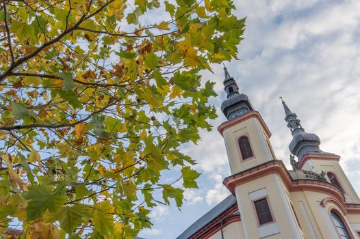 Beautiful scene of tower of castle in Litomysl with autumn leaves in foreground.