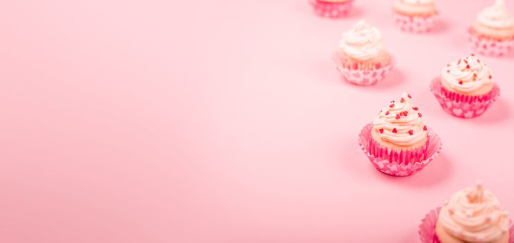 Valentine day love cupcakes decorated with cream and hearts on pink background with copy space for text