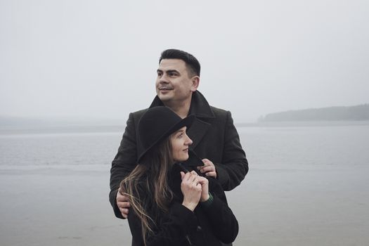 Loving young couple enjoying a romantic moment together in a close embrace on a romantic date on a misty cold lake shore in winter