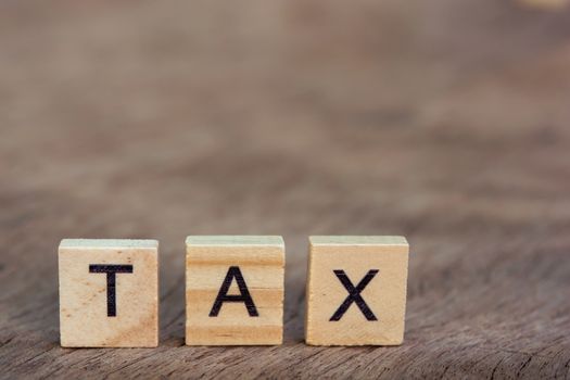 Tax with wooden alphabet blocks, on plank wooden background with copy space
