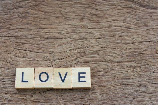 Text wooden blocks spelling the word love on wooden background