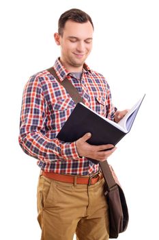 Portrait of a smiling young male student in stylish plaid shirt outfit with a shoulder bag holding and looking at an open notebook, isolated on white background.