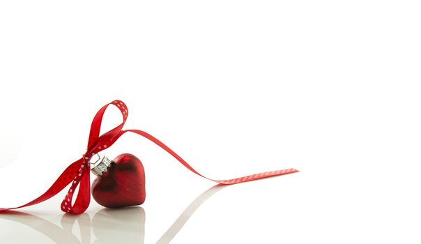 red heart for Christmas with a bow of a red ribbon isolated on white ribbon