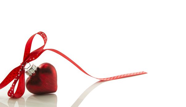 red heart for Christmas with a bow of a red ribbon isolated on white ribbon