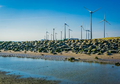 wind mill park with rocks and water on the beach distance view