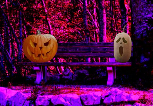 Halloween two scary carved pumpkins on a park bench in a spooky forest landscape