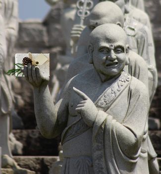 Christmas Buddhist monk statue holding a present with a blank card and pointing at it
