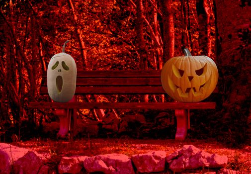 Halloween celebration two scary and spooky carved pumpkins on a park bench in a horror forest landscape