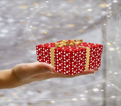 Isolated hand holding a decorated wrapped present and giving it away on a christmas background with stars