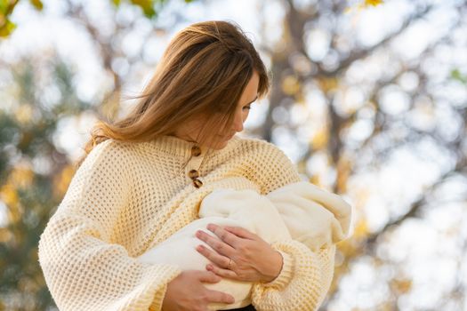 Young girl feeds newborn baby in park