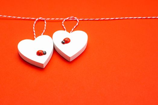 Blank for the designer. Valentines day concept. Greeting card. Copy space.Valentine's Day. White wooden hearts on a red background and red ladybugs.