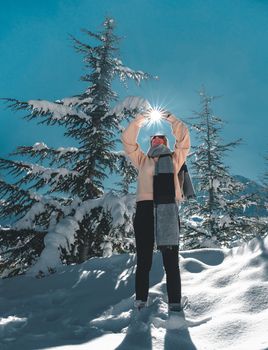 Happy adult woman holding sun between her hands with blue sky the background.