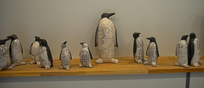 Ceramic figurines of penguins on wooden shelf